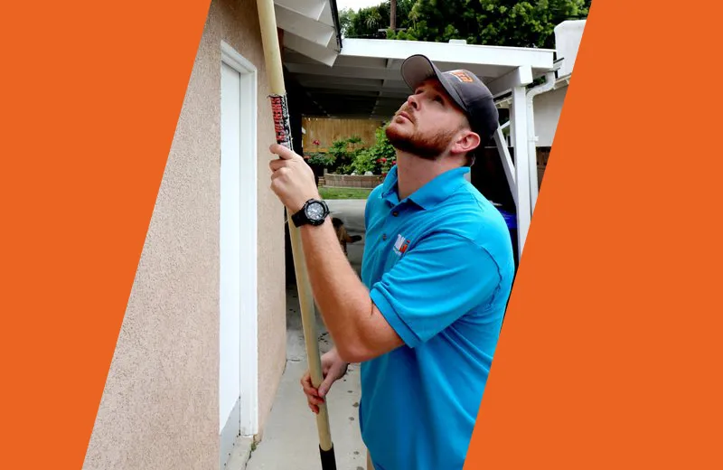 Pest Technician sweeping exterior of home